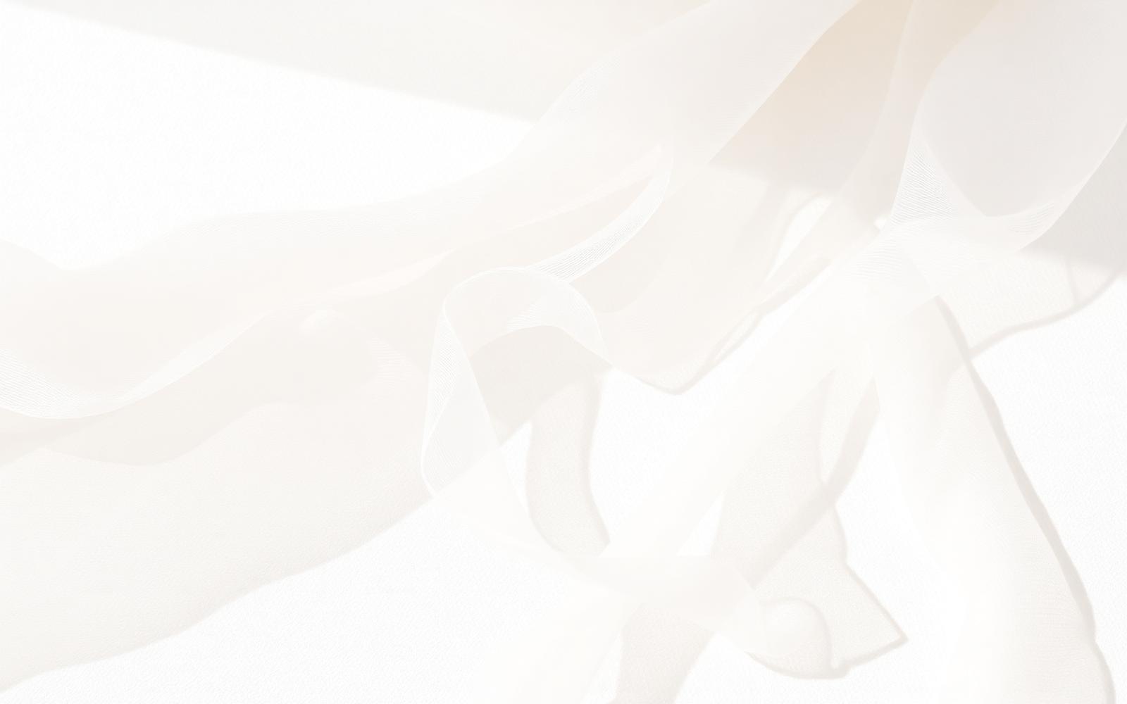Fine sheer fabric draped softly across a pale surface in gentle light